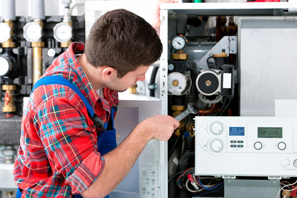 HVAC technician inspecting and repairing boiler controls in Peoria